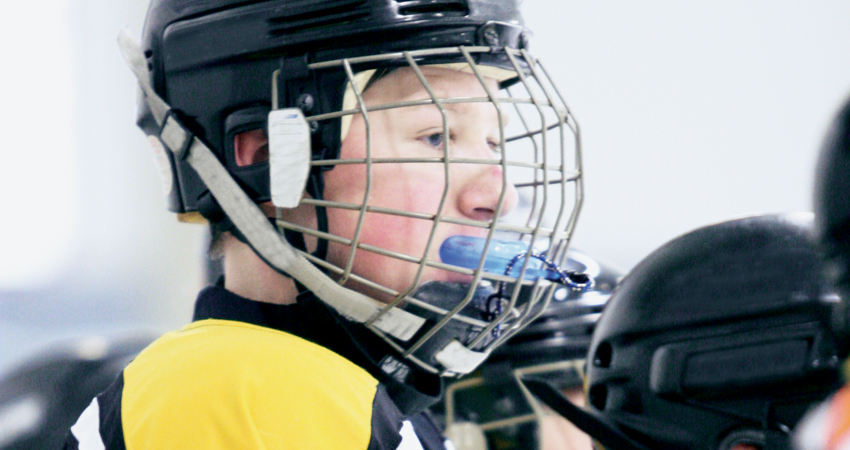 Young hockey player with mouthguard coming out of mouth
